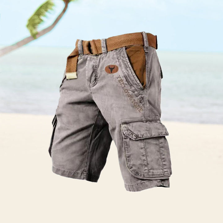 Male model wearing knee-length cargo shorts with multiple pockets on a plain background.