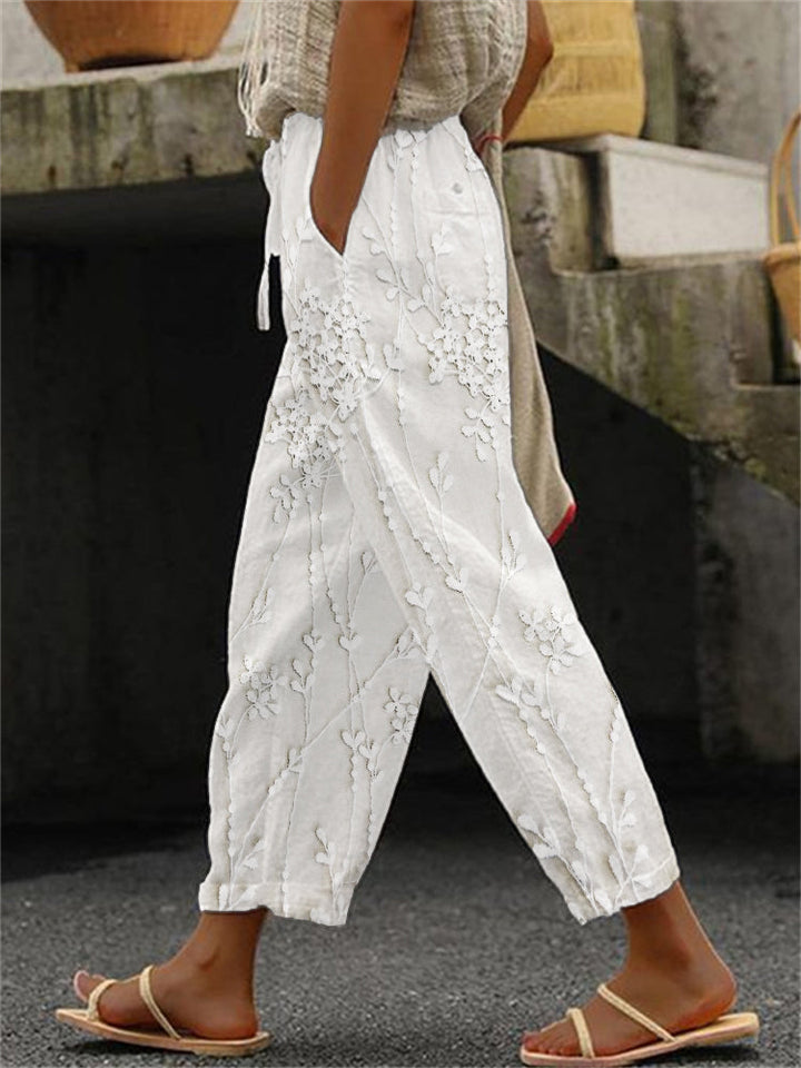 Female wearing stylish patterned trousers on a plain studio background.