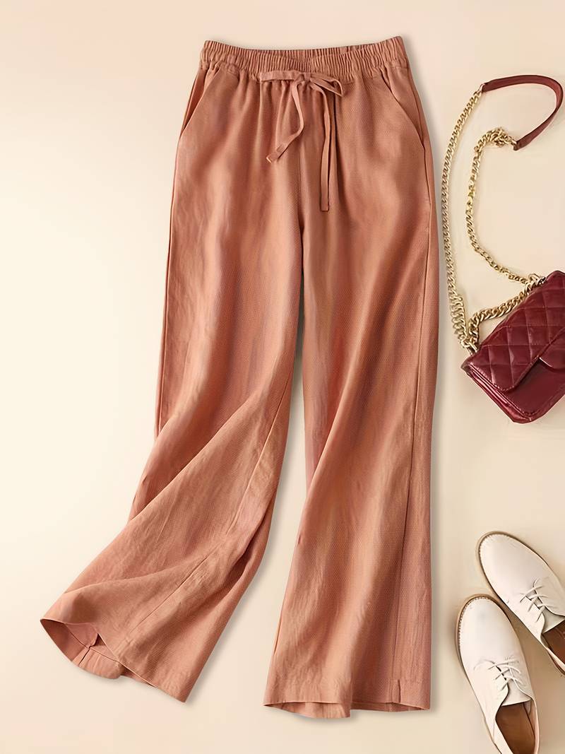 Women’s casual wide-leg pants with soft fabric drape on a beige background.