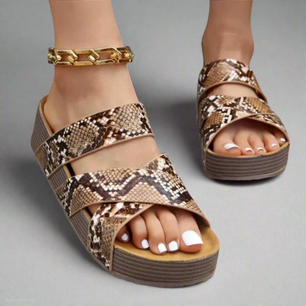 Foot wearing breathable sandal on plain studio background.