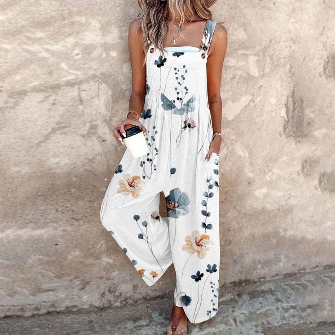 Female model wearing a floral wide-leg jumpsuit with adjustable shoulder straps against a plain background.