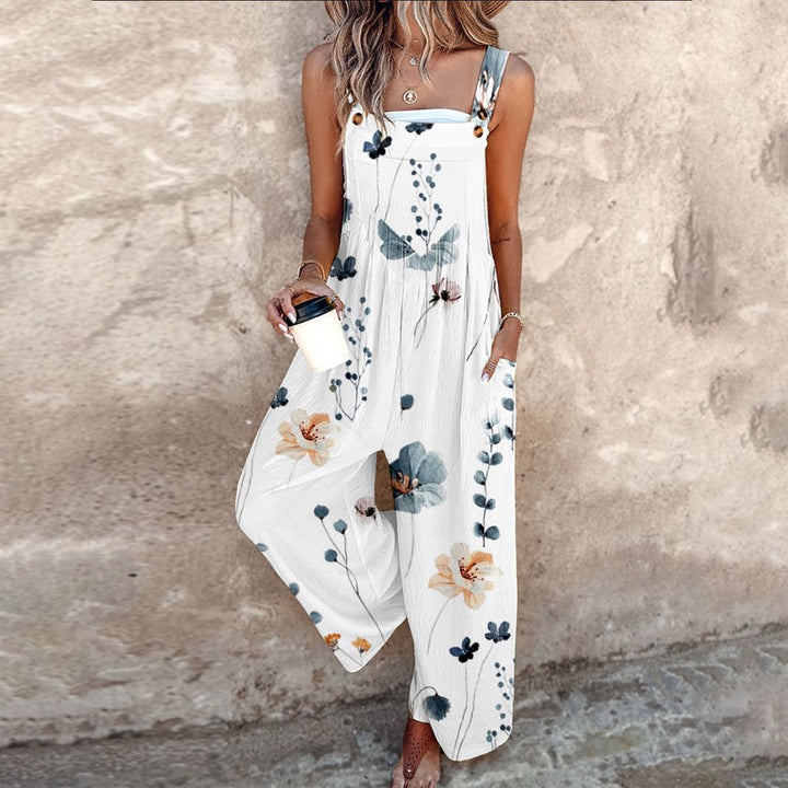 Female model wearing a floral wide-leg jumpsuit with adjustable shoulder straps against a plain background.