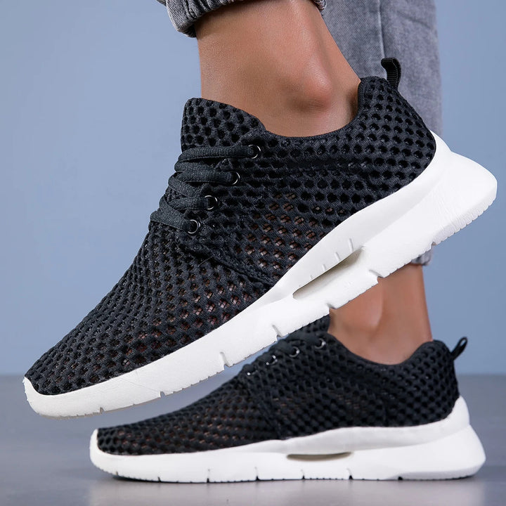 Casual mesh sneakers worn by a woman on a plain background.