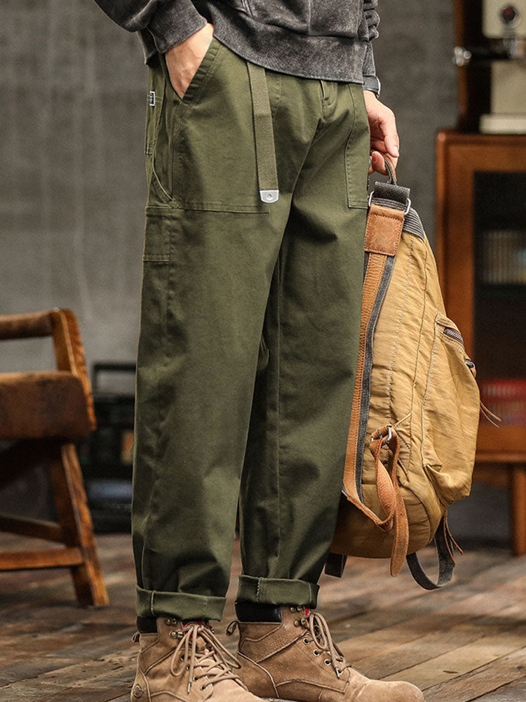 Male model displaying workwear-inspired cargo pants with utility details against a plain background.