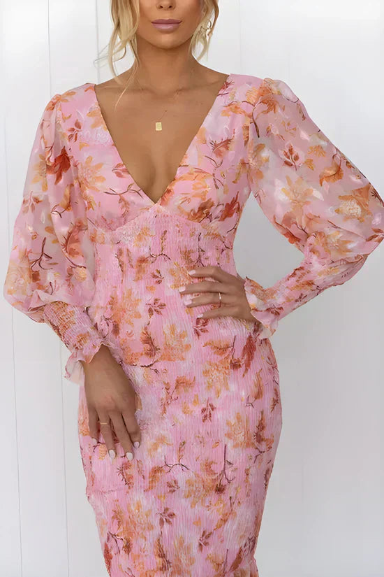 Woman showcasing a flowing floral dress with a plain background.