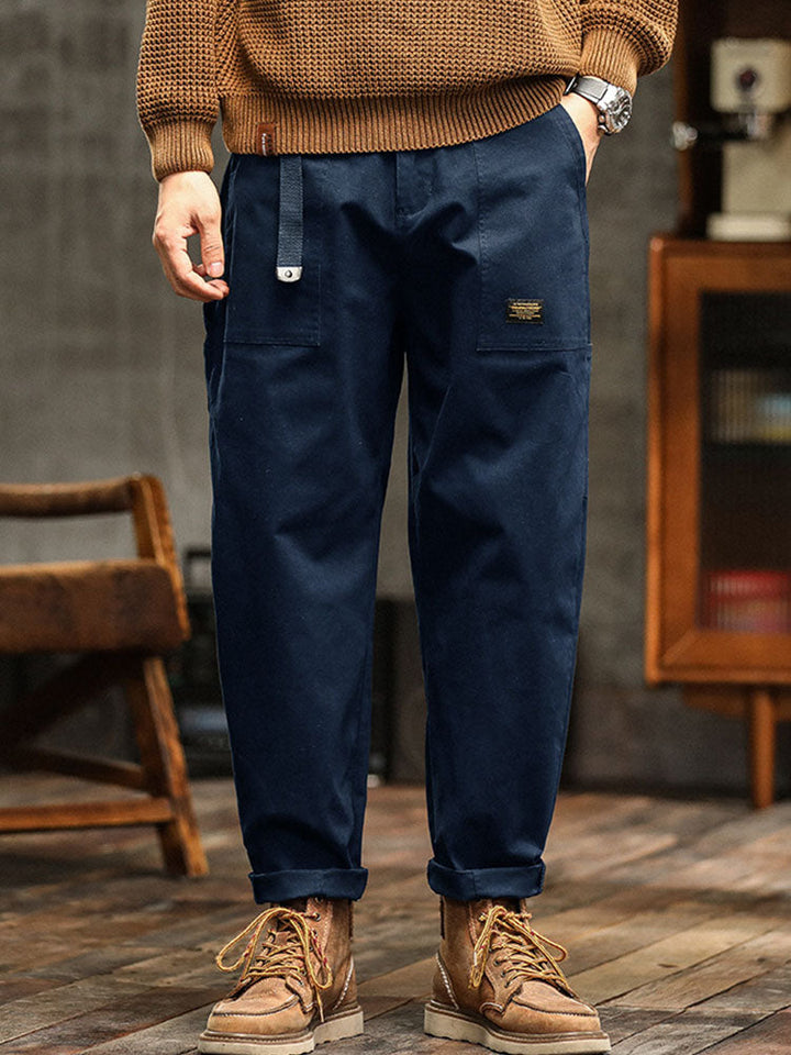  Male model showcasing wide-leg cargo trousers with rolled cuffs on a plain background.