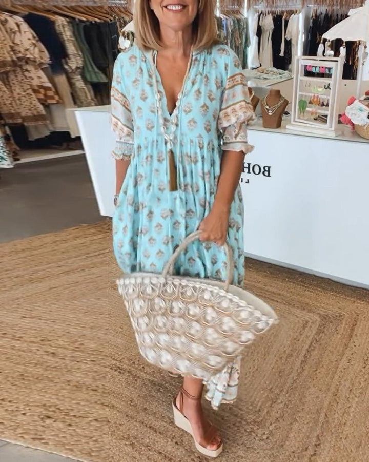 Boho midi dress displayed on a plain background with flowing shape and tassel accents.