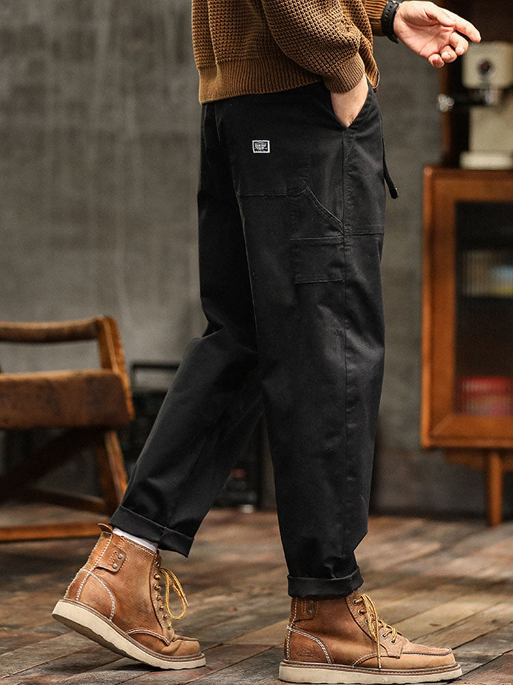 Male model showcasing utility-inspired cargo trousers with a modern fit on a plain background.