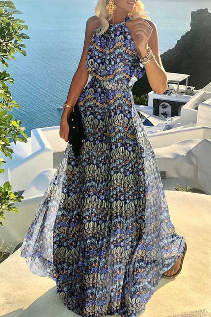 Female wearing a floor-length pleated dress with an open halter neckline against a nature background.