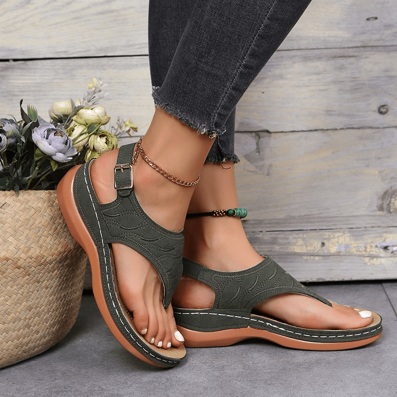 Female model in elegant women’s sandals with a cushioned footbed on a plain background.