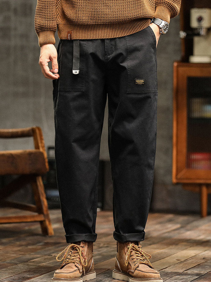 Male model in casual utility pants featuring side cargo pockets against a plain background.