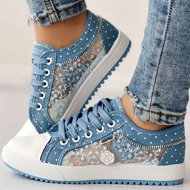 Female feet wearing casual walking sneakers on a plain background.