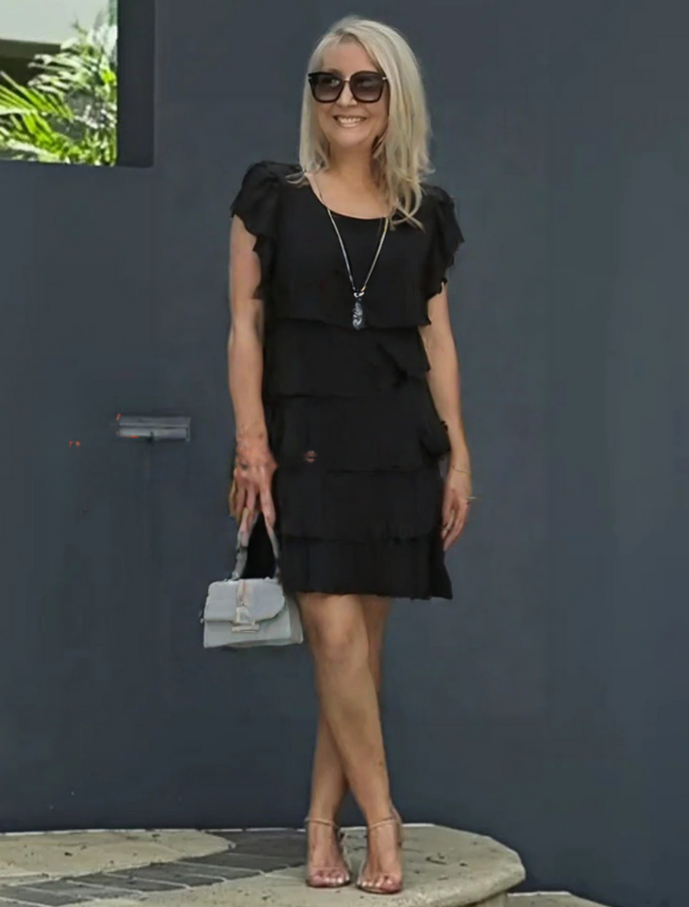 Model showcasing a layered midi dress for semi-formal wear on a plain background.