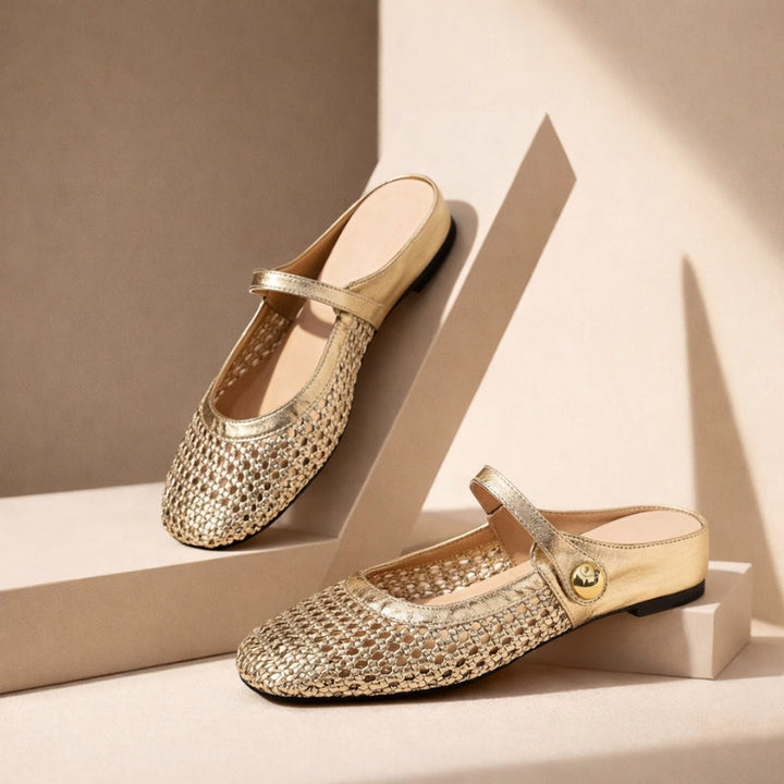 Female model styling woven mule flats with relaxed trousers on a plain background.