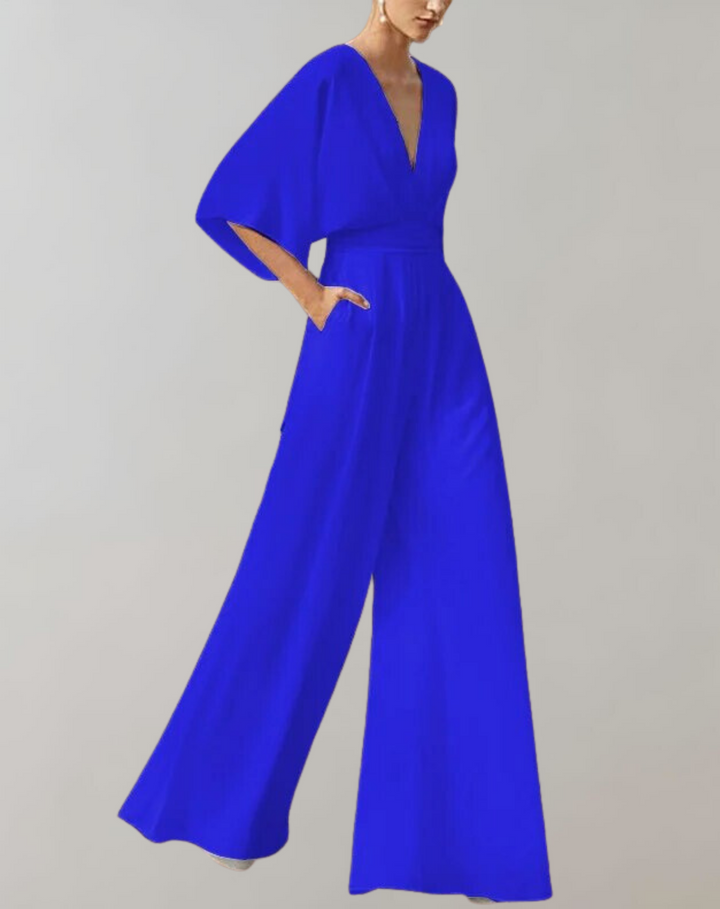 Female model showcasing an elegant full-length jumpsuit with dramatic sleeves.
