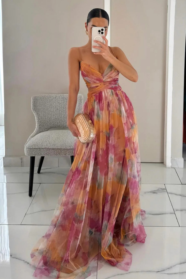 Woman wearing a flowing maxi dress against a plain background.