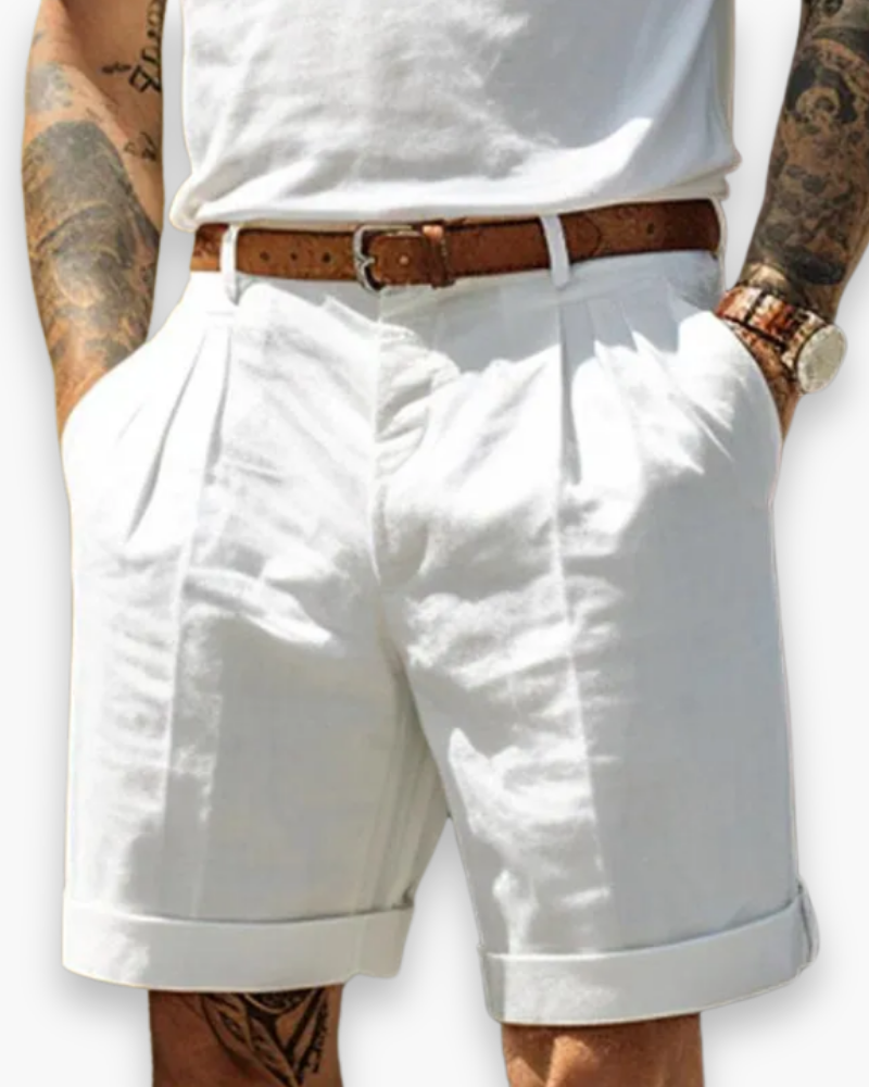 Model wearing tailored chino shorts with pleated front on a plain background.