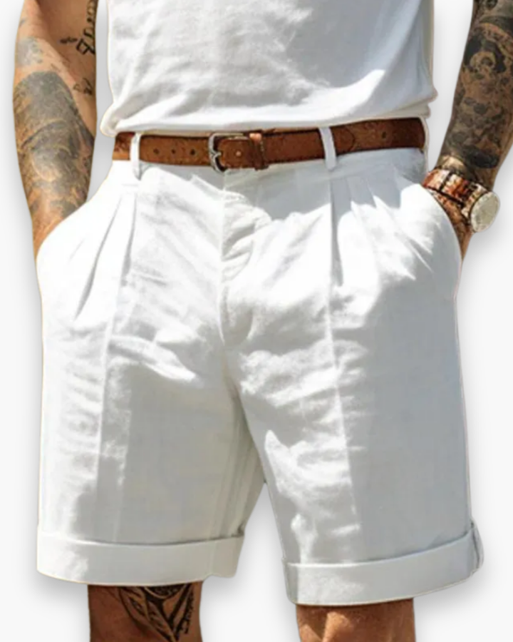 Model wearing tailored chino shorts with pleated front on a plain background.