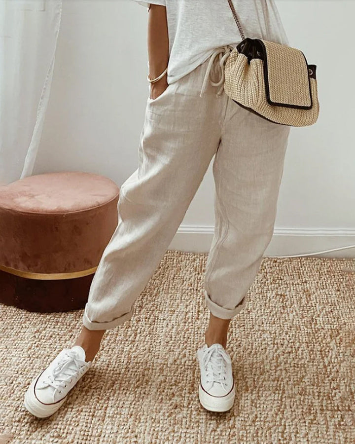 Woman wearing elegant waistband trousers on a plain background.
