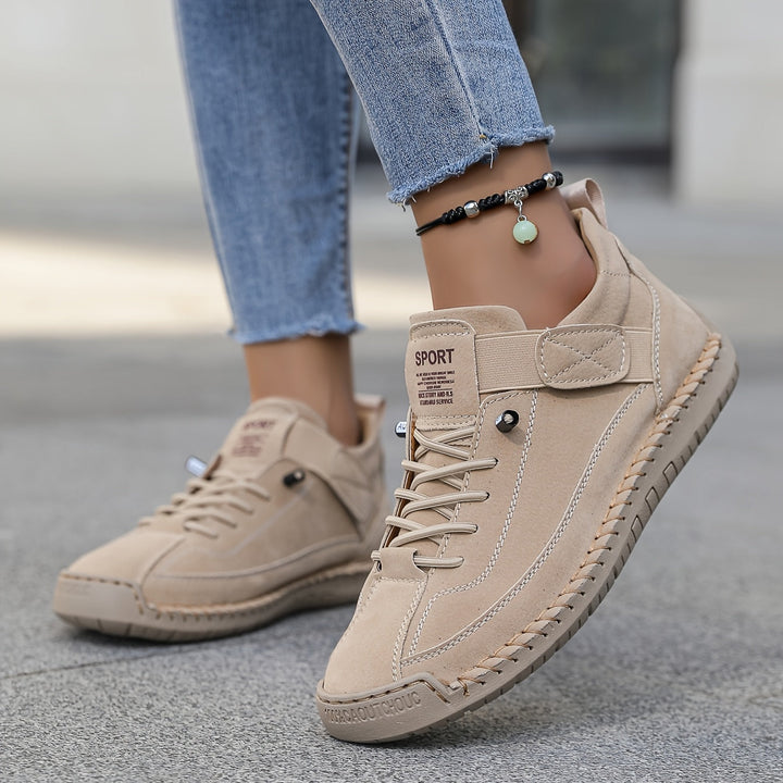Woman standing in casual slip-on sneakers with strap detail on a plain background.
