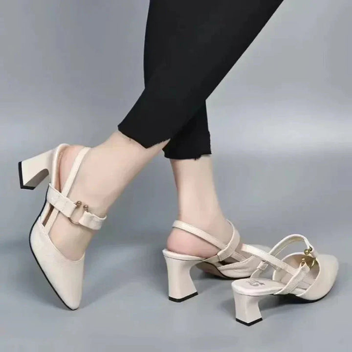 Woman showing versatile heeled sandals with secure straps on a plain background.