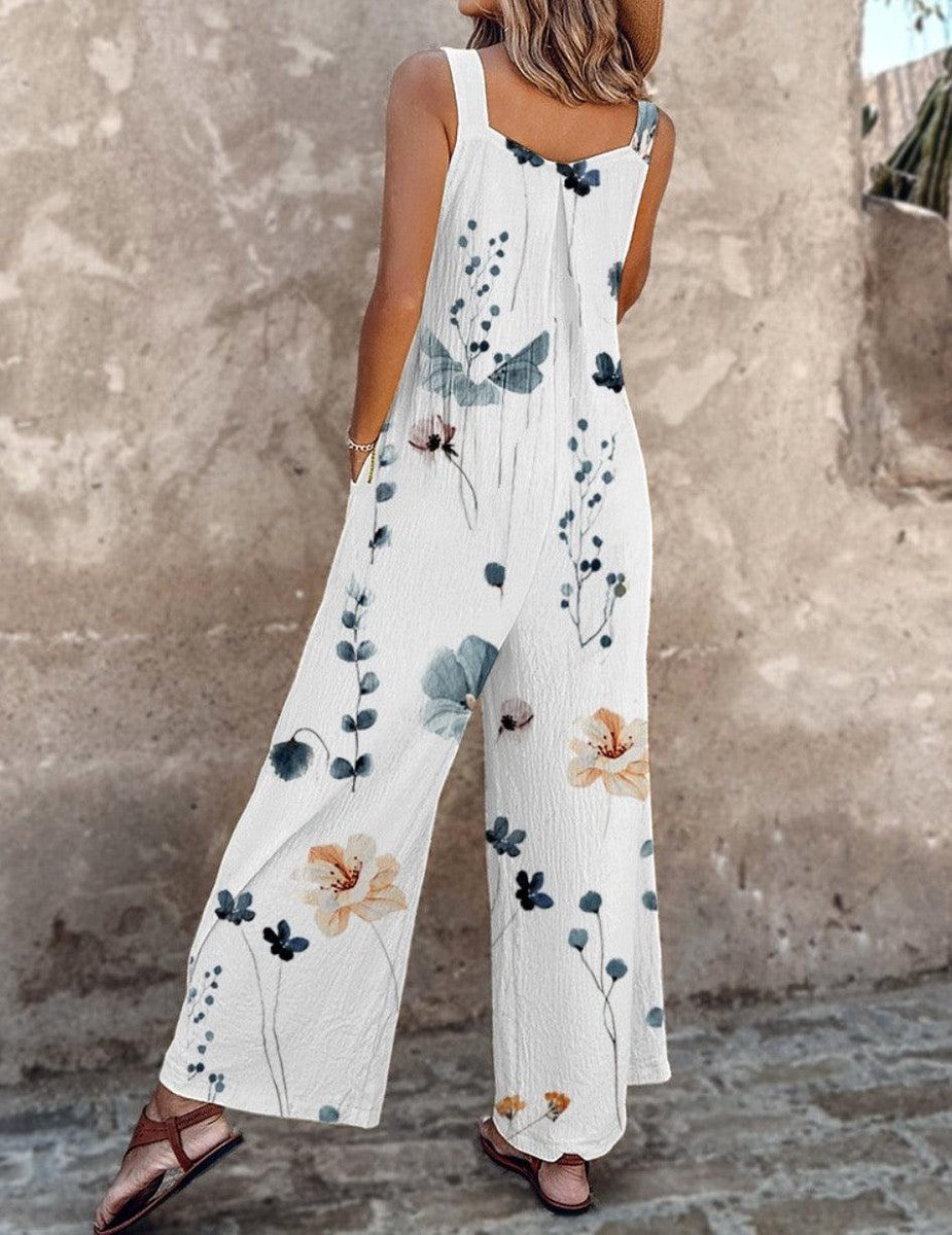  Female model in a relaxed floral one-piece featuring adjustable straps and side pockets on a plain background.