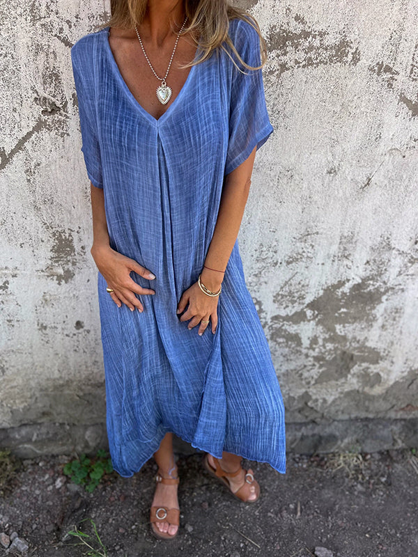 Female model in a stylish full-length dress photographed on a plain background.
