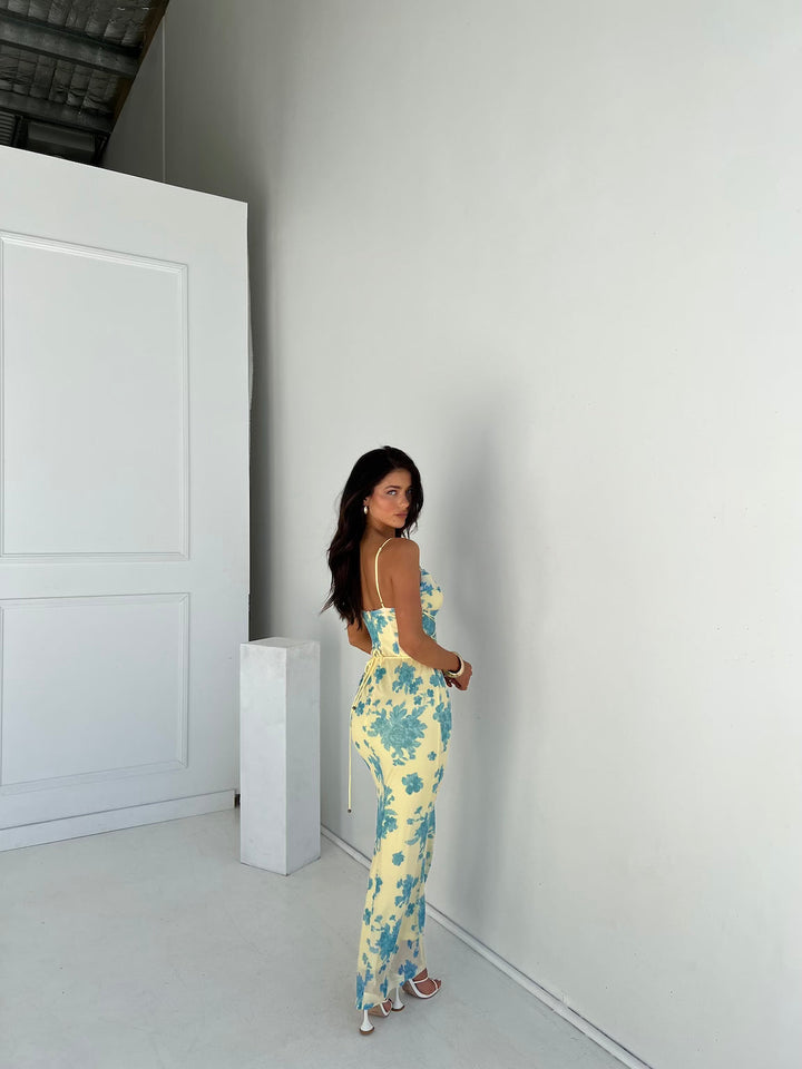 Model wearing a feminine floral maxi dress against a plain setting.