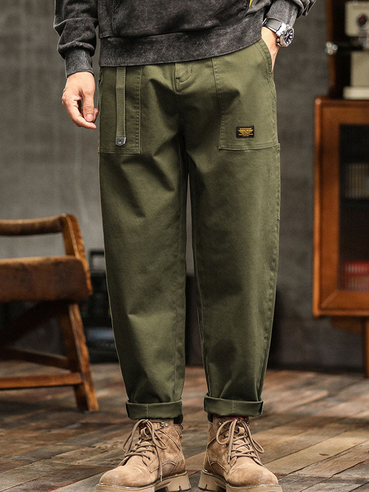 Male model wearing relaxed cargo pants with utility pockets against a plain background.