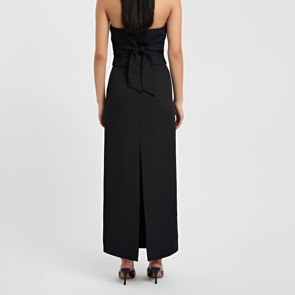 Woman showcasing a long skirt with a graceful silhouette on a plain background.