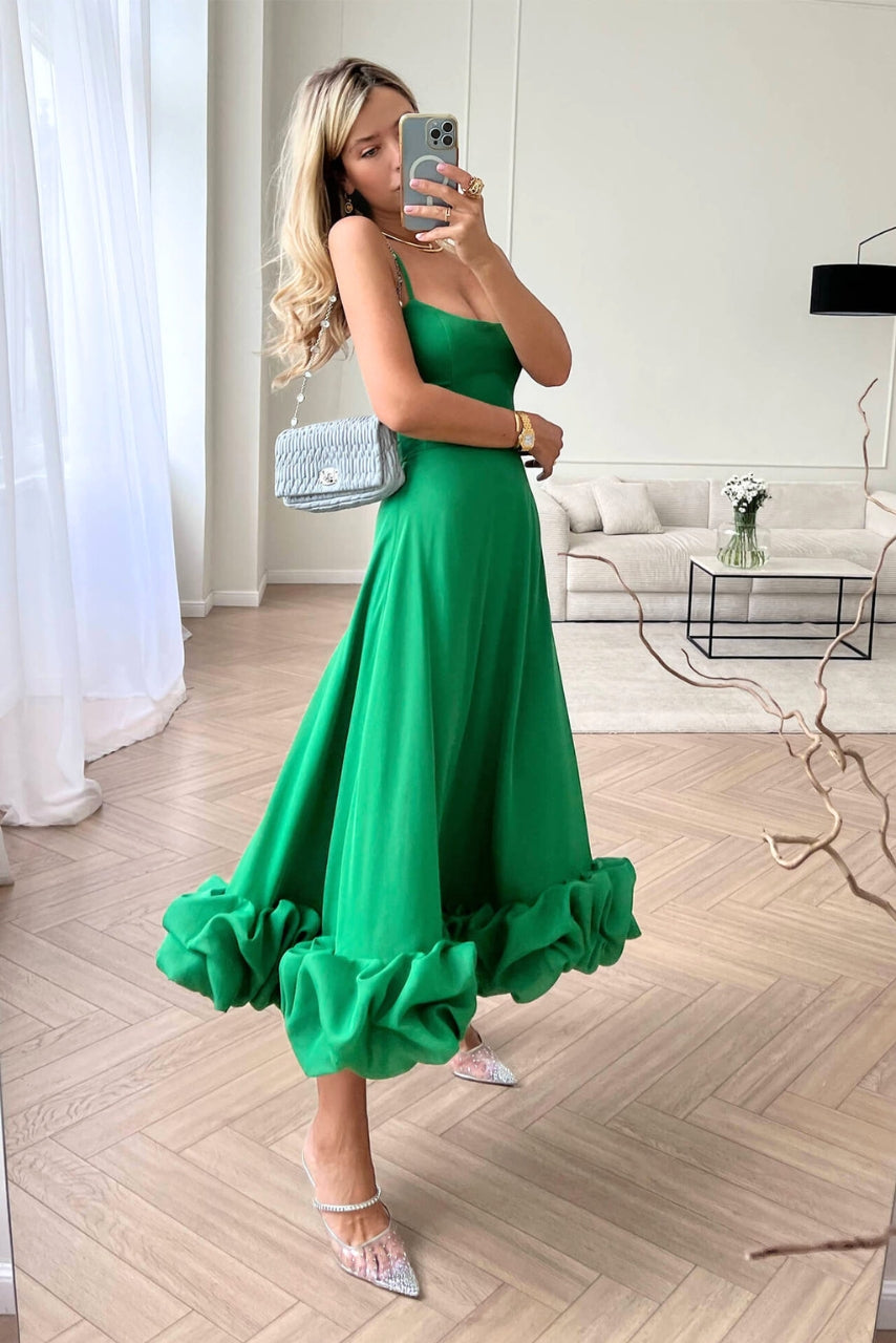 Model in a feminine draped dress with a clean backdrop.