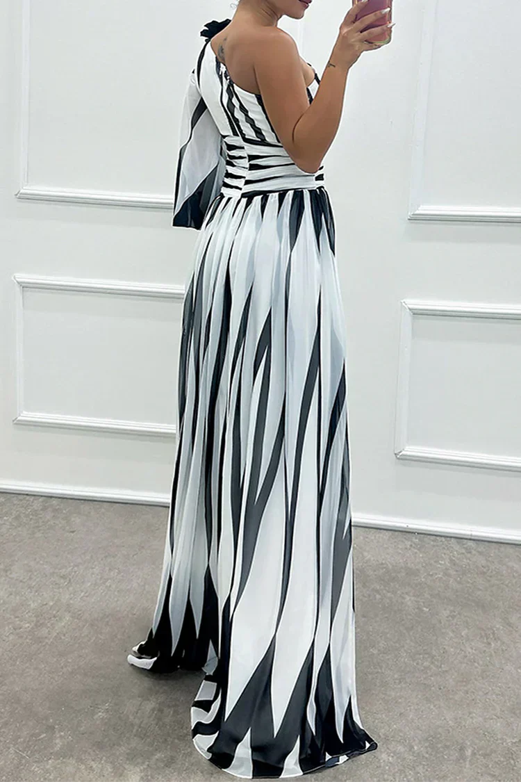 Woman showcasing an asymmetrical striped maxi dress with a plain background.