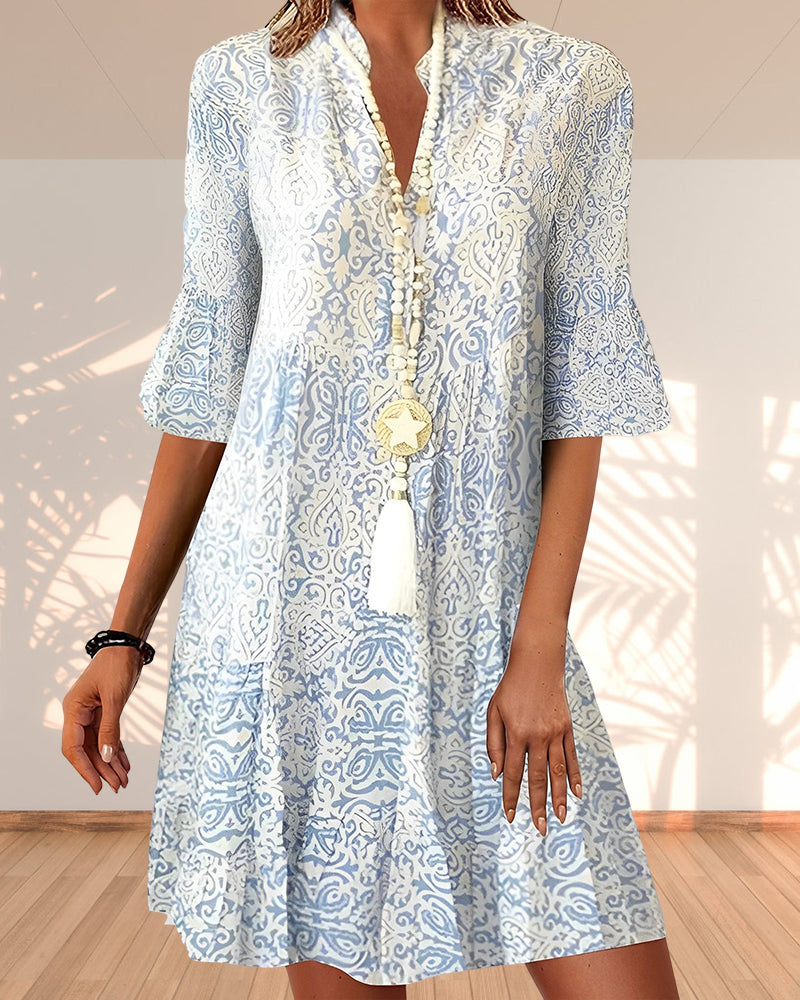 Woman wearing a blue paisley swing dress posing against a plain background.