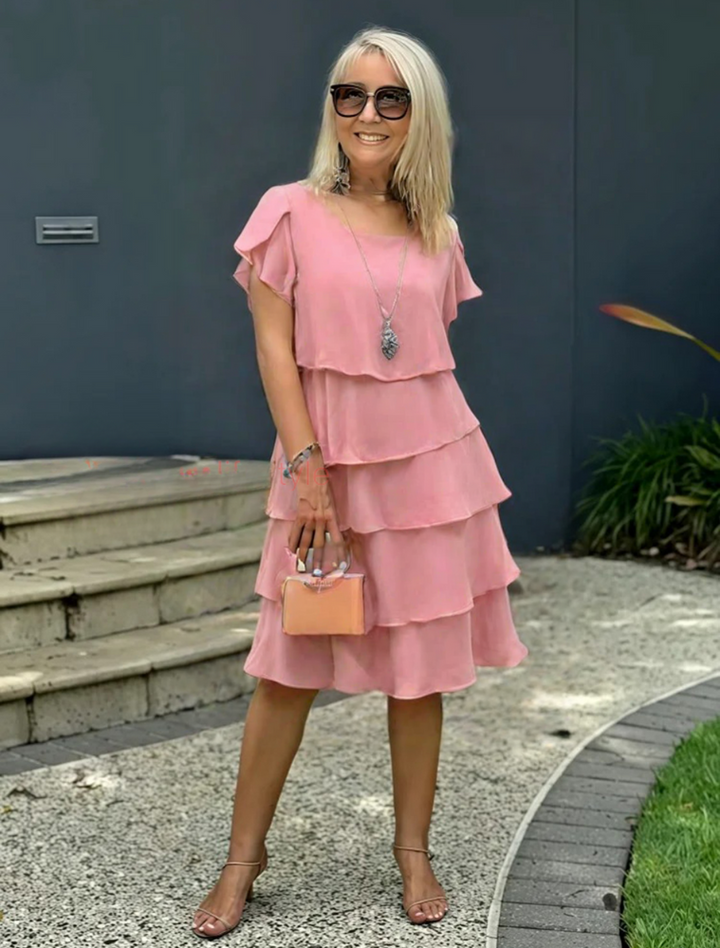 Female model wearing a graceful short sleeve midi dress on a plain background.