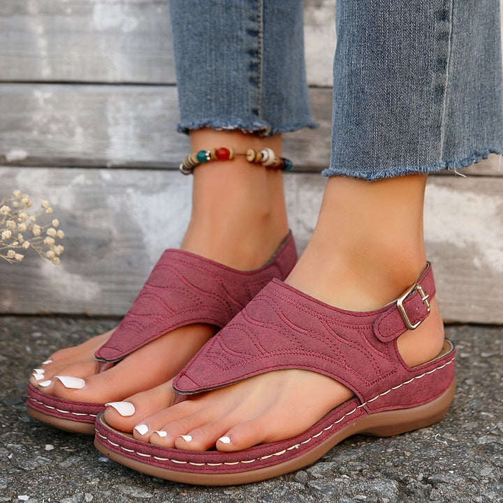 Female model standing in summer clip toe sandals on a plain background.
