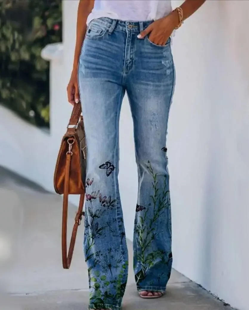 Statement denim jeans with retro floral print on plain backdrop.