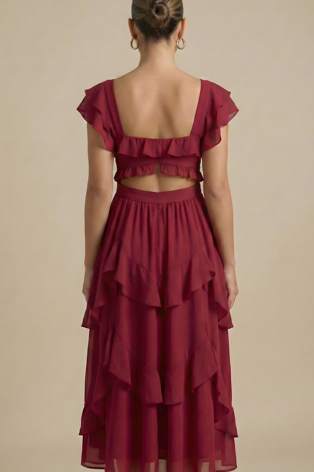 Model in a flowing midi dress with cascading skirt panels and soft flutter sleeves on a plain background.