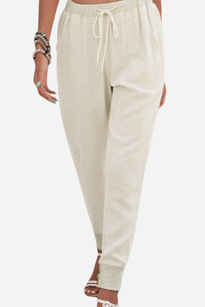 Woman wearing elastic ankle pants with a drawstring waist on a plain background.