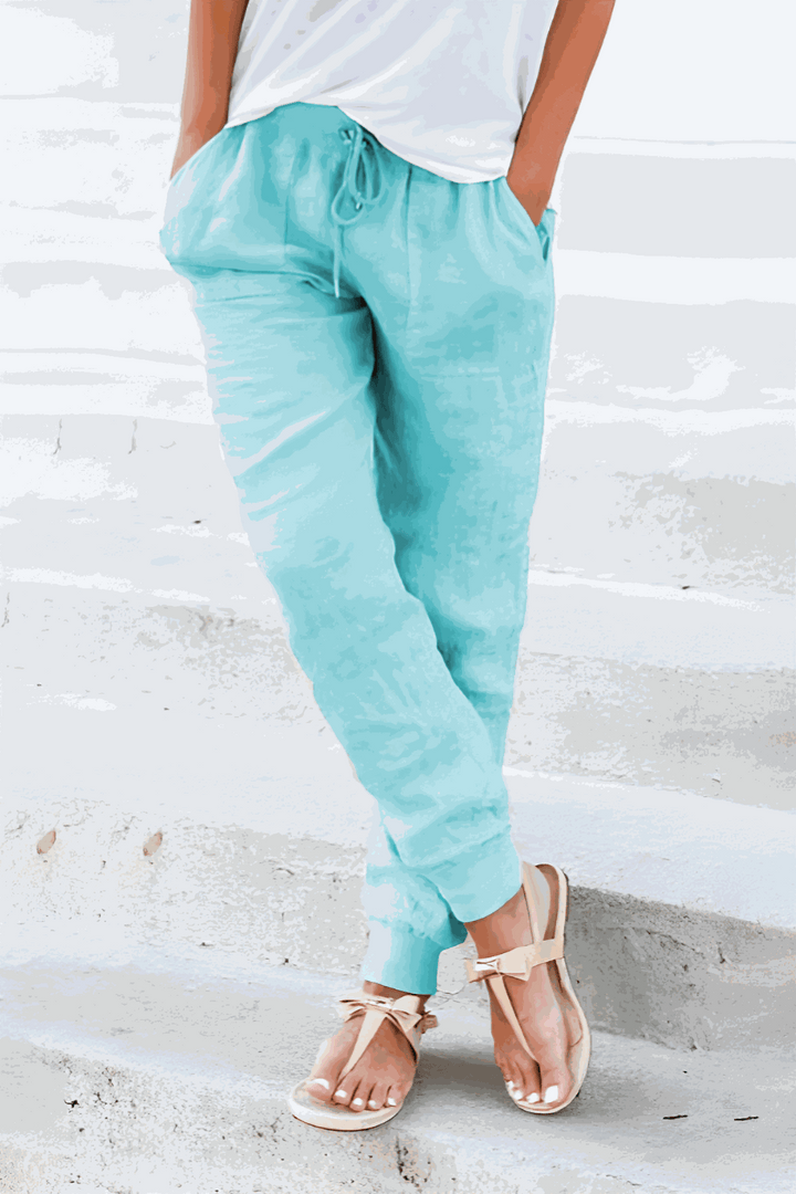 Female model showing casual ankle pants with drawstring detail on a plain background.