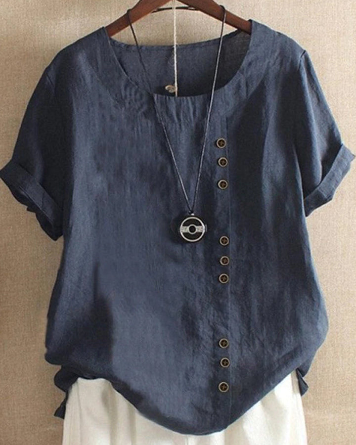 Elegant buttoned blouse in natural linen on plain backdrop.