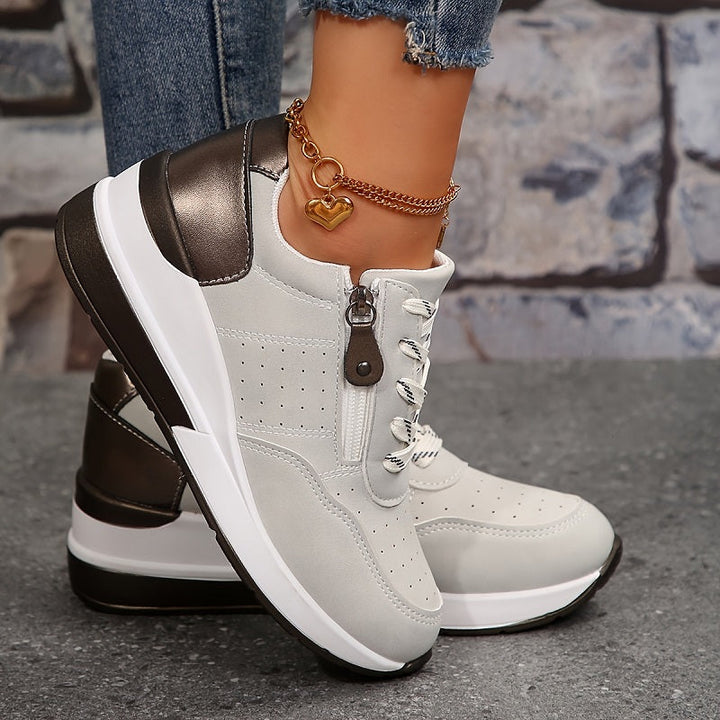 Female wearing stylish low-top sneakers against a plain background.
