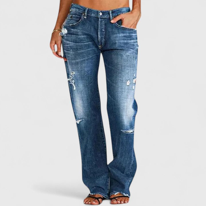 Female model wearing distressed flare jeans against a plain background.