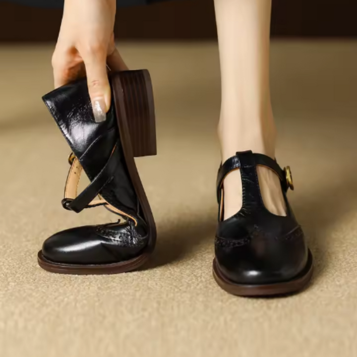 Woman wearing square toe flat mules with woven detail on a plain background.