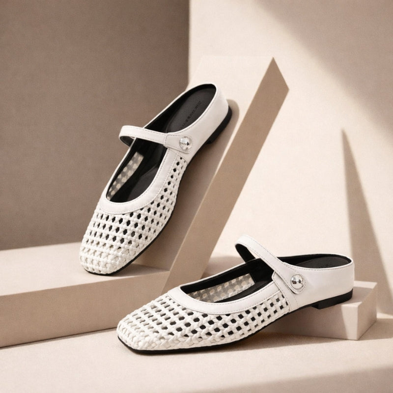 Woman wearing square toe woven slip-on shoes on a plain background.