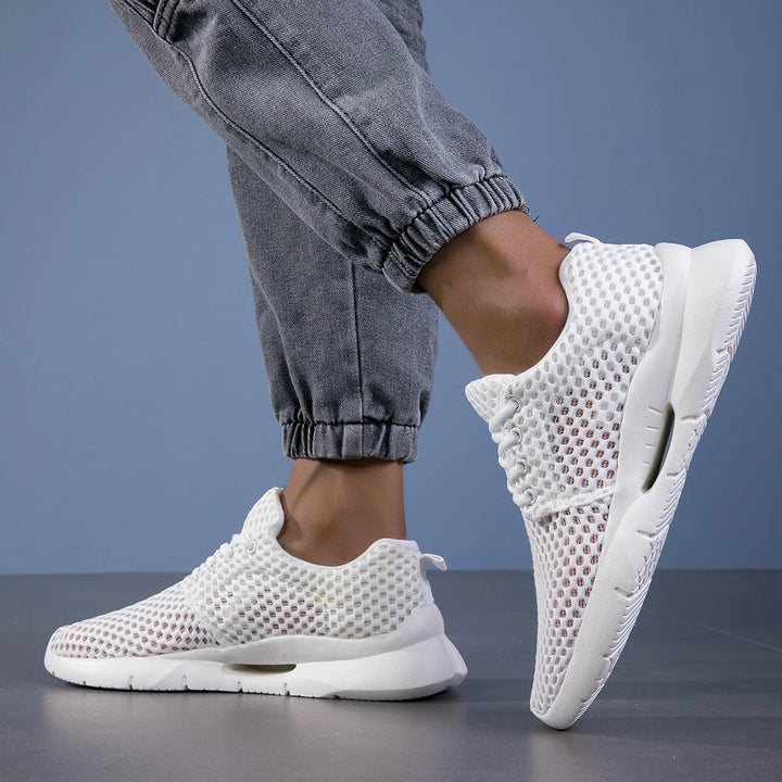 Close-up of feet wearing flexible walking sneakers on a plain background.