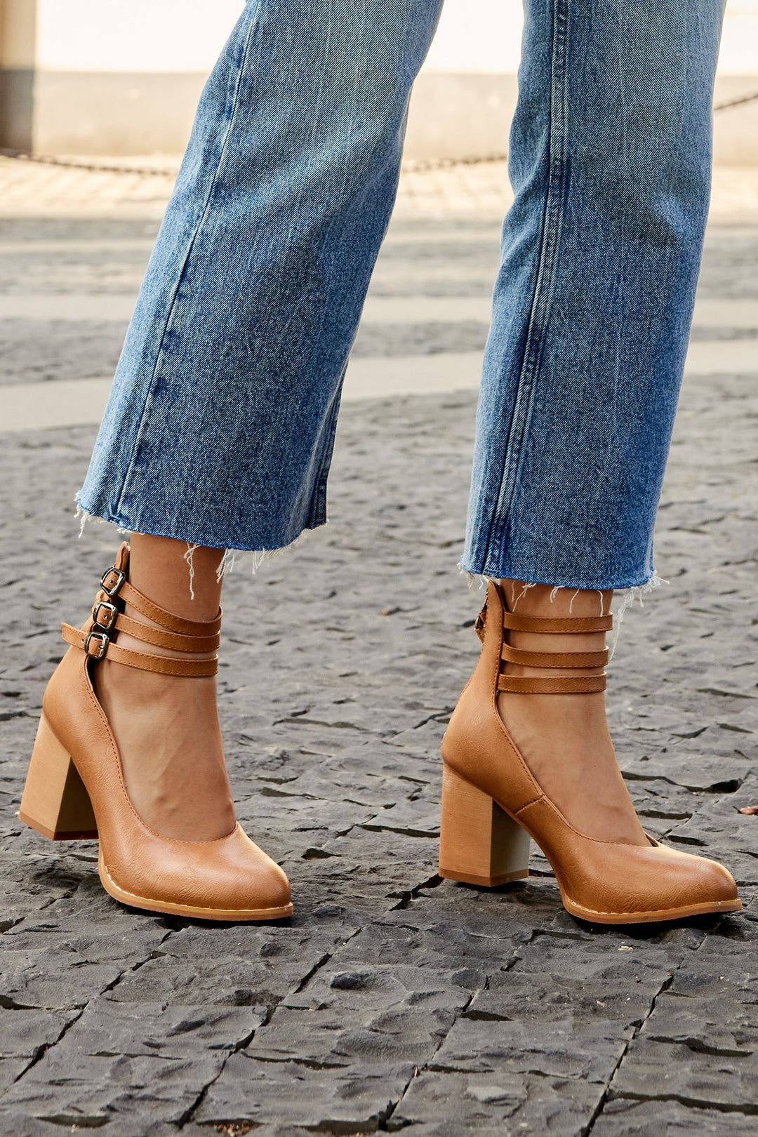 Foot in a refined block heel sandal with a smooth minimalist silhouette.