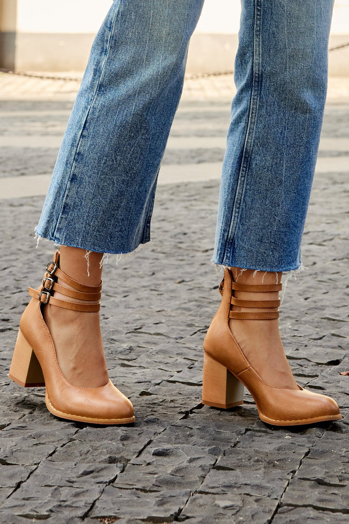 Foot in a refined block heel sandal with a smooth minimalist silhouette.