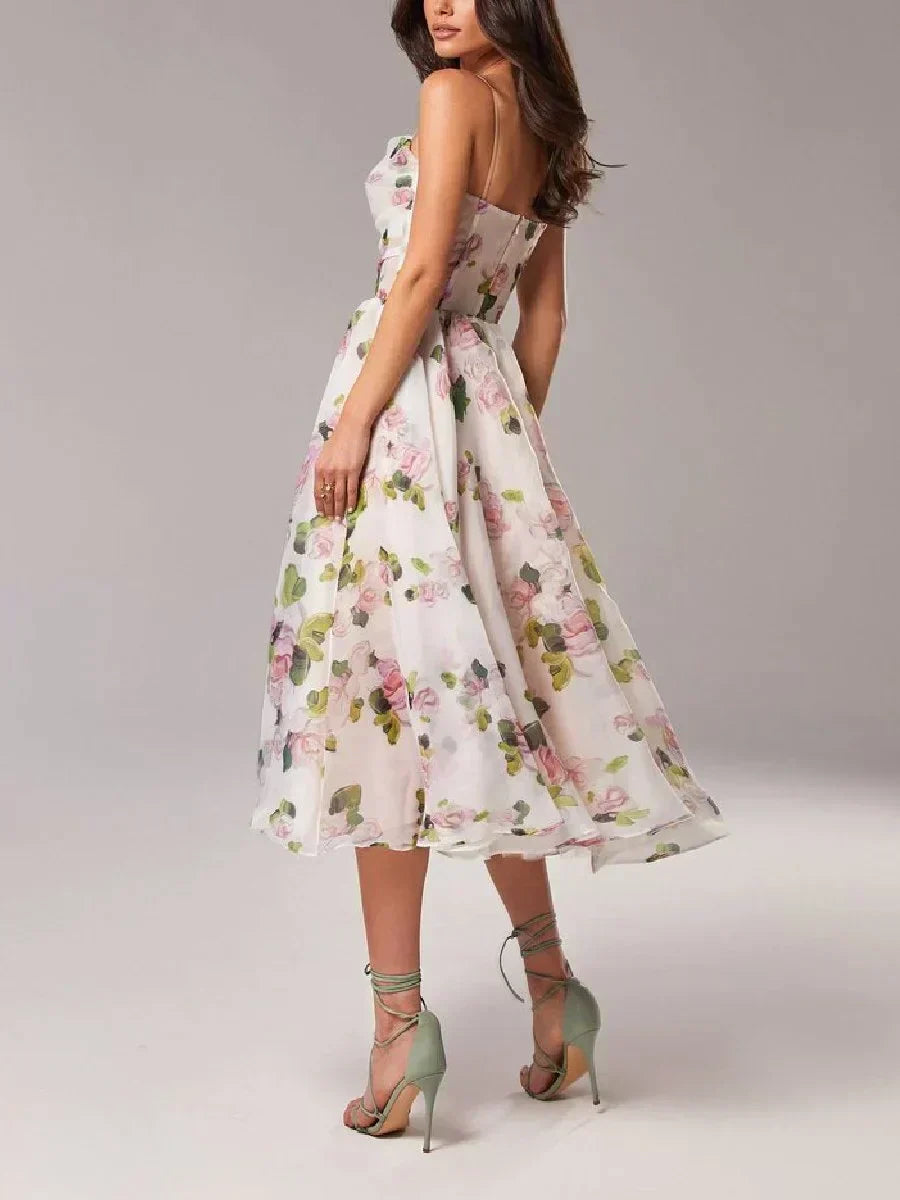 Woman wearing a midi dress with an all-over floral pattern and full skirt against a plain background.