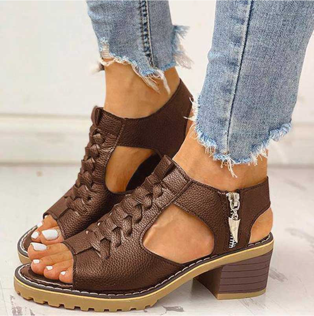 High heel sandals displayed with feet only against a plain background highlighting sleek straps and elevated design.