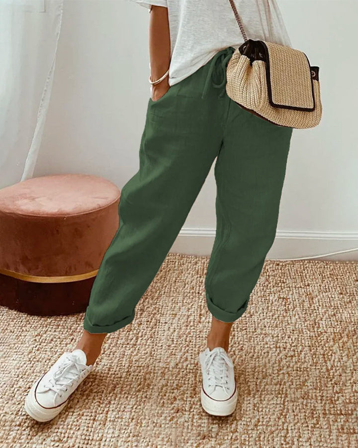 Female model showcasing relaxed fit trousers on a plain background.